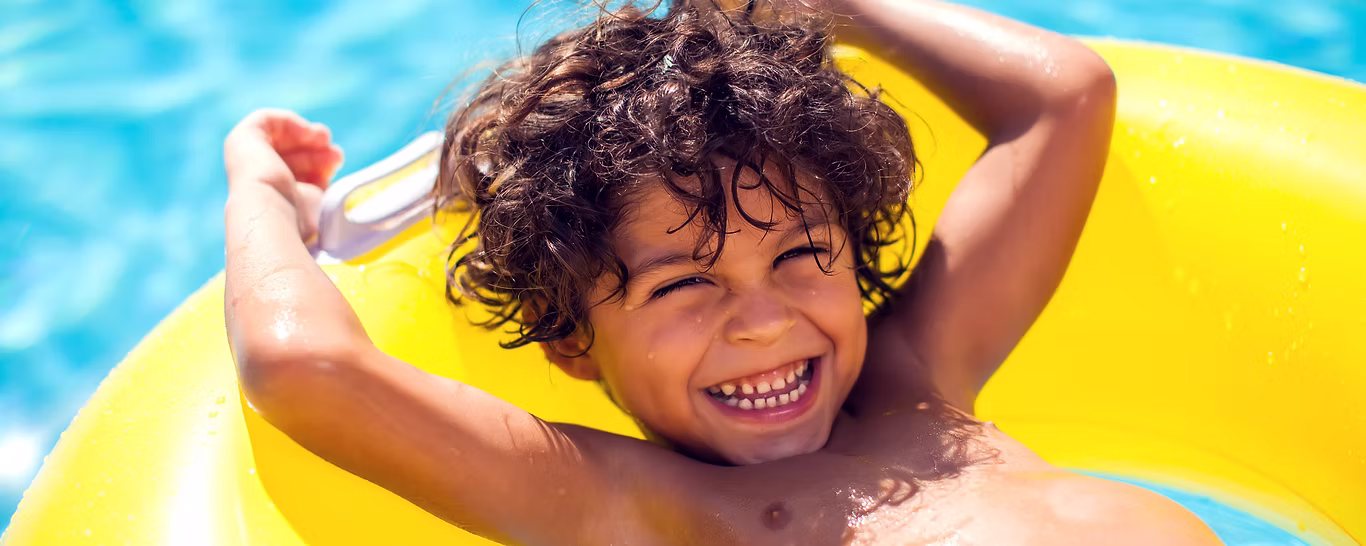 Criança sorrindo enquanto boia em uma piscina